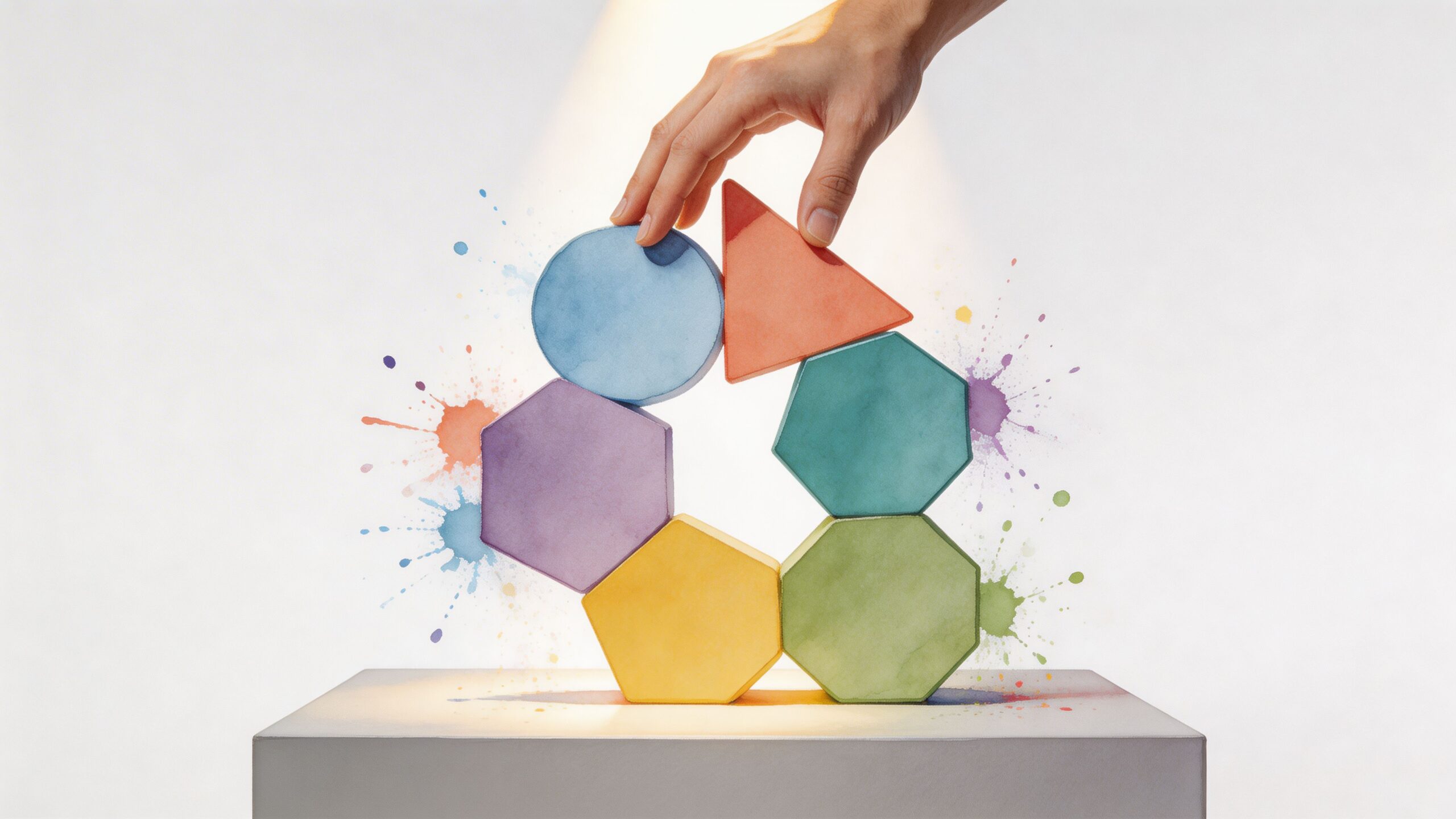 A hand placing a geometric block onto a colorful arrangement of shapes on a white platform.