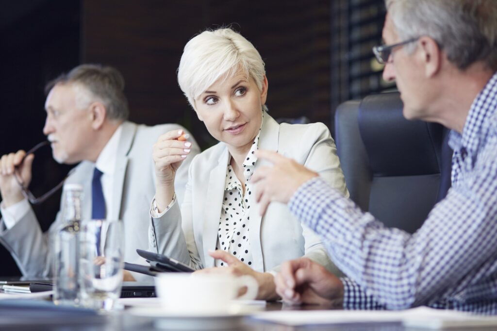 Three business professionals discussing decisions around a conference table.